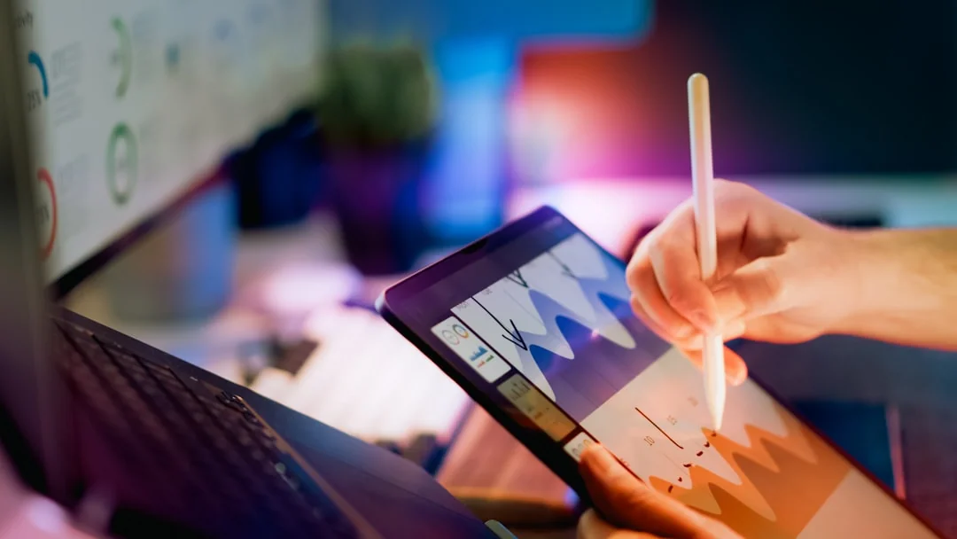 Une équipe variée travaillant ensemble sur des stratégies de marketing digital autour d’une table, utilisant ordinateurs portables et tablettes.